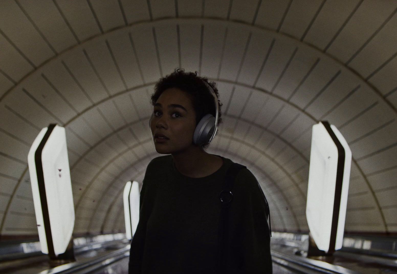 a woman wearing headphones standing in a tunnel