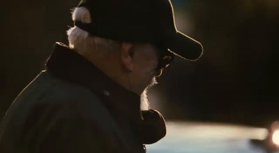 a man wearing a hat and sunglasses walking down a street