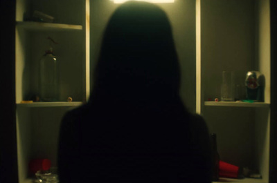 a woman standing in front of a mirror in a dark room