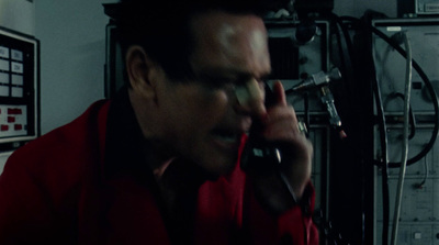 a man in a red shirt talking on a cell phone