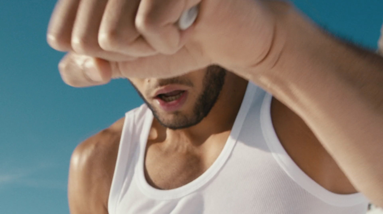 a man in a white tank top holding a cell phone