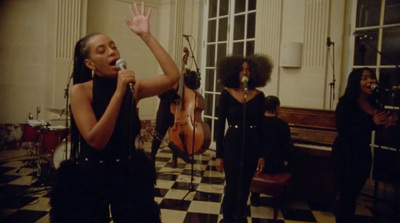 a woman singing into a microphone in front of a group of people