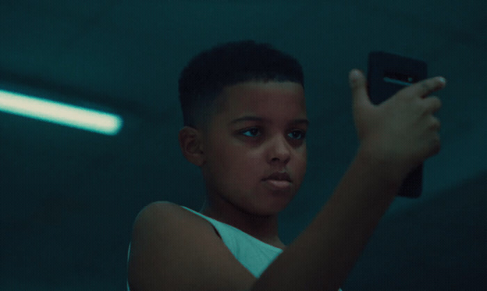 a young boy holding a cell phone in a dark room