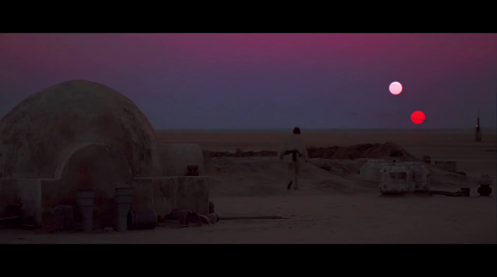 a man standing in front of a red ball in the middle of a desert