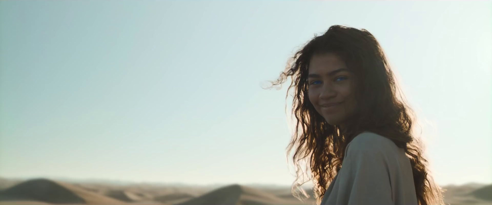 a woman with long hair standing in the desert