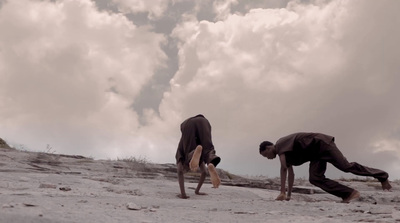 a couple of men standing on top of a sandy beach