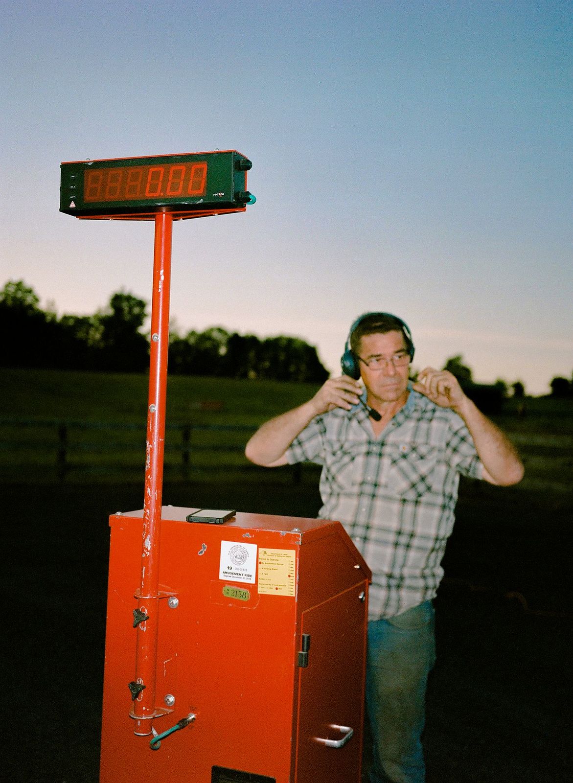 a man standing next to a red box talking on a cell phone