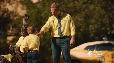 a man in a yellow shirt and tie standing next to two children