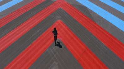 a person standing on a runway with red and blue stripes