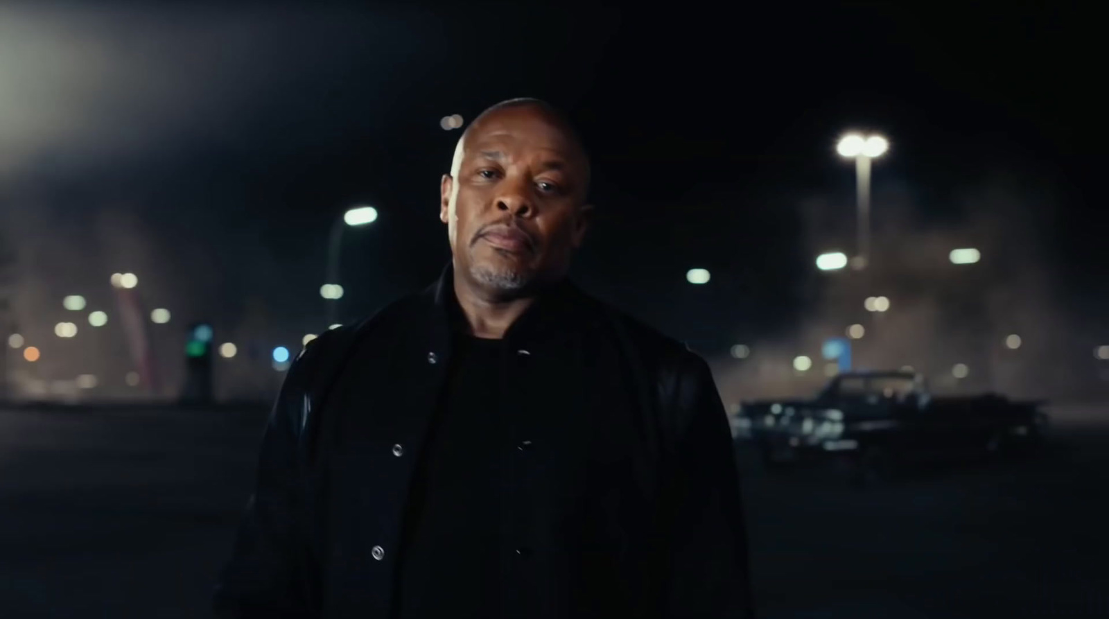 a man standing in a parking lot at night