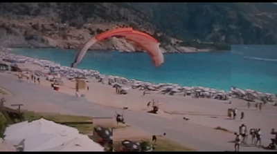 a large red kite flying over a sandy beach