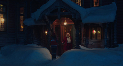 a woman in a red coat is standing outside of a house