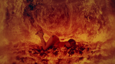 a woman laying on the ground in front of a fire