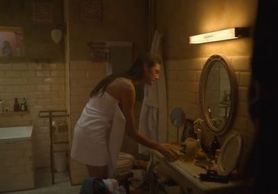 a woman in a bathrobe standing in front of a sink