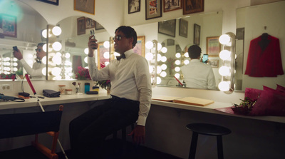 a man sitting in front of a mirror in a dressing room