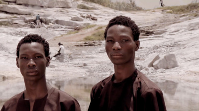 two young men standing next to each other near a body of water