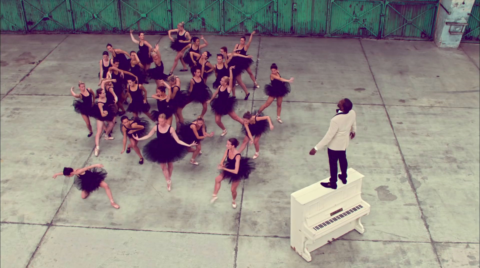 a man standing on top of a piano next to a group of dancers