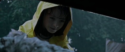 a young girl in a yellow raincoat looking at something