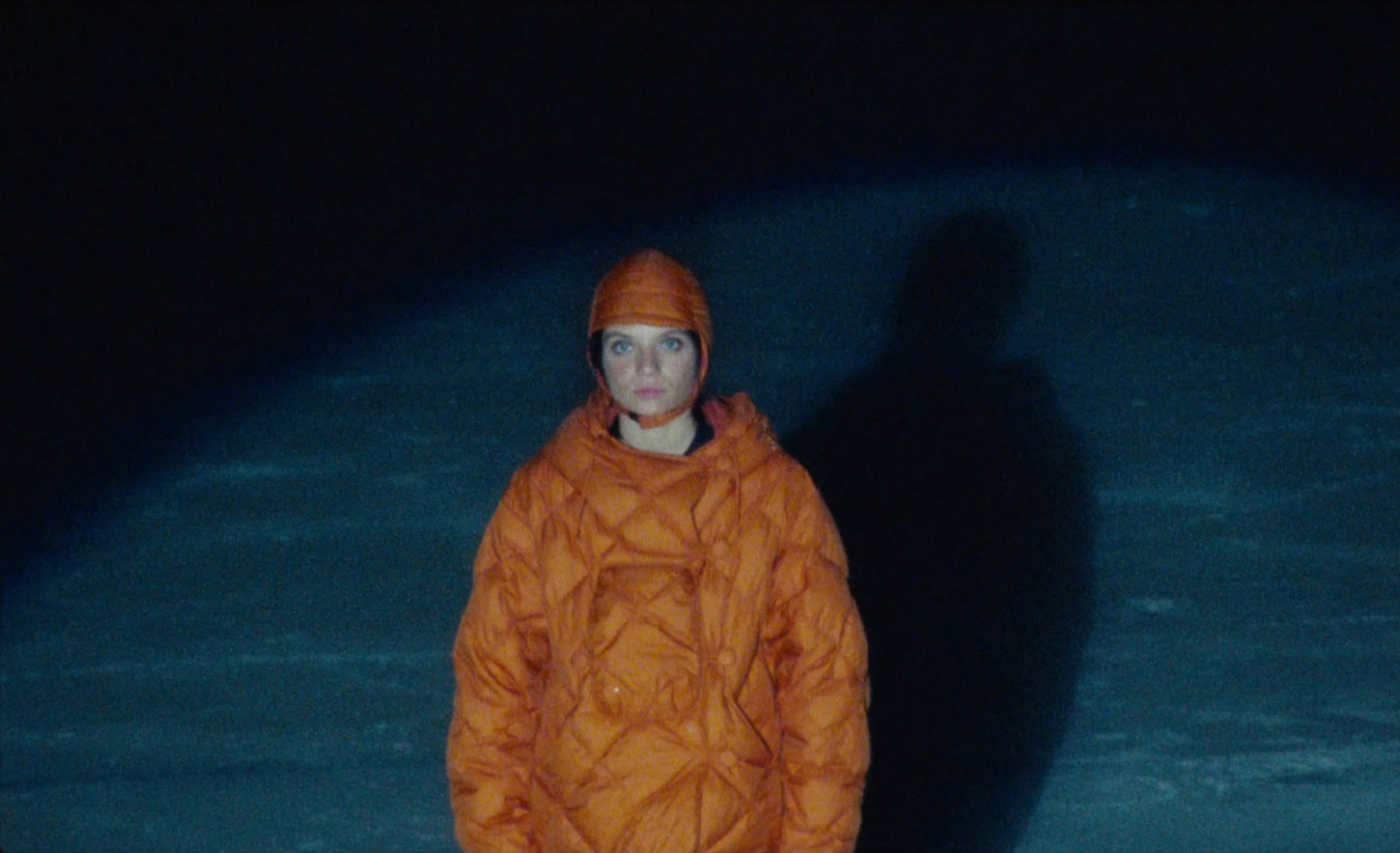 a person in an orange coat standing in the dark