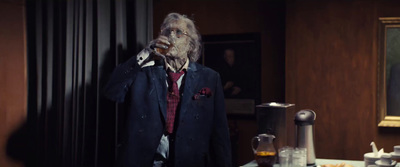 a man in a suit and tie drinking from a bottle