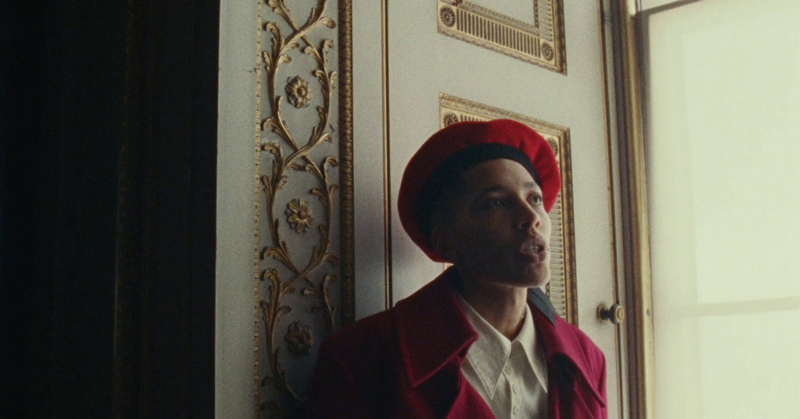 a man wearing a red hat standing in front of a door