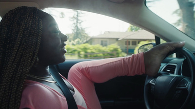 a woman driving a car with braids on her hair