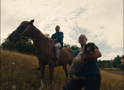 a man holding a dog while riding a horse