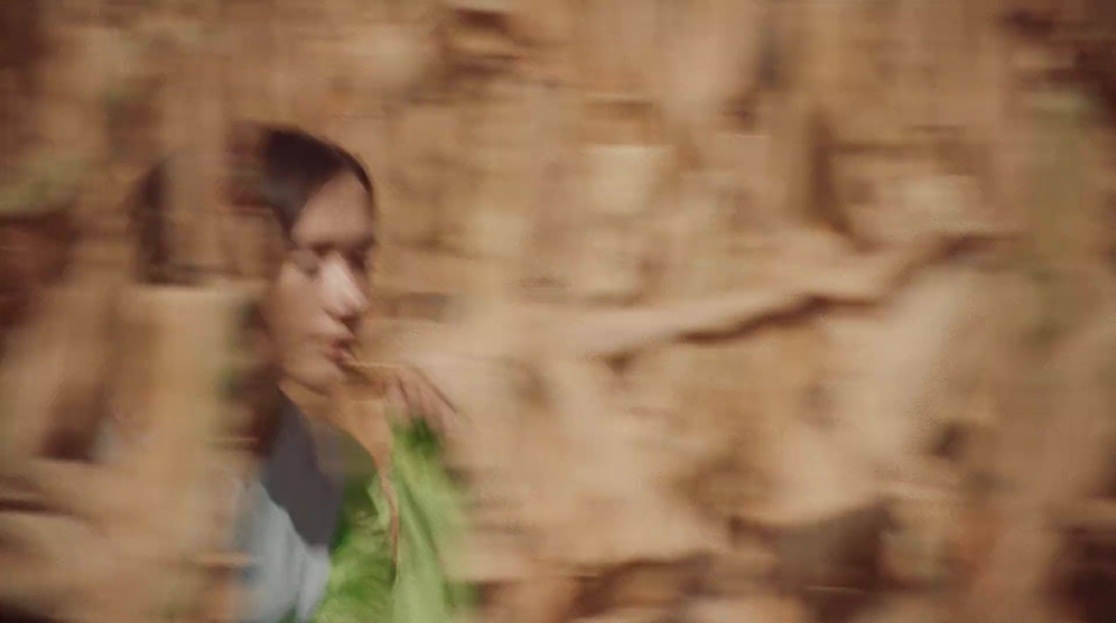 a blurry photo of a man standing in front of a rock wall