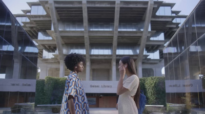 two women standing in front of a building talking on a cell phone