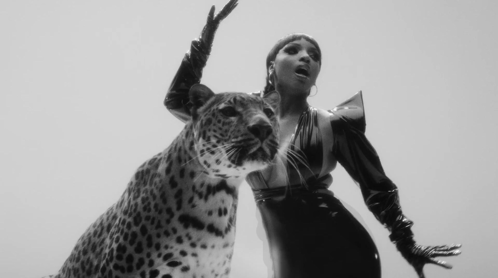 a woman standing next to a large leopard