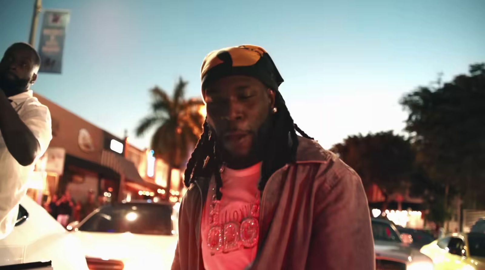 a man with dreadlocks standing in front of a car