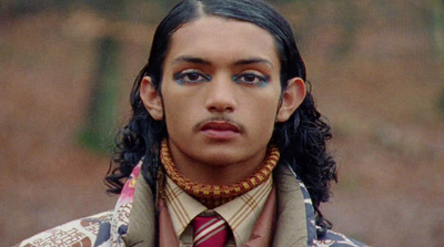 a man with long hair wearing a neck tie