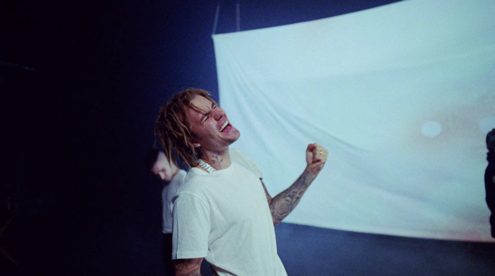 a man with dreadlocks standing in front of a projection screen