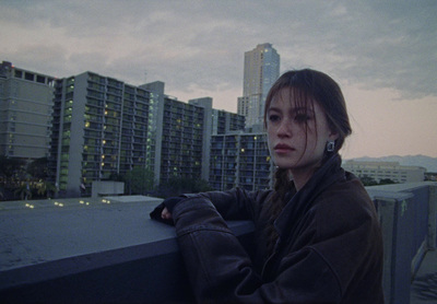 a woman leaning on a ledge in front of a cityscape