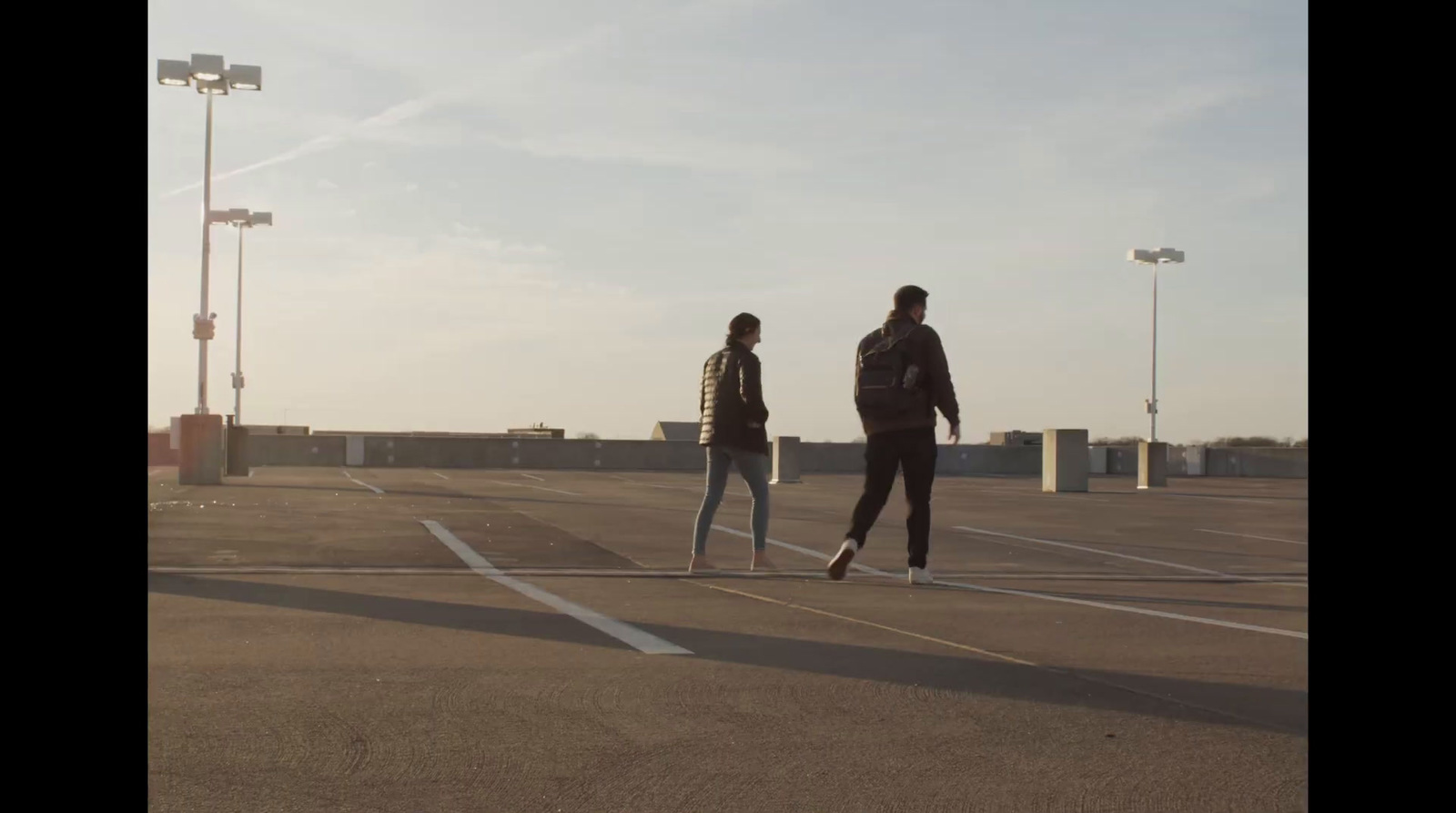 a couple of people walking across a parking lot