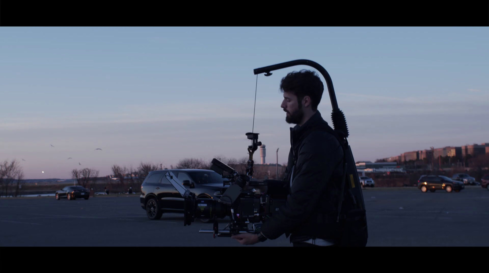 a man walking across a parking lot next to a car