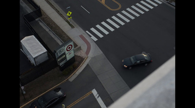 a black car driving down a street next to a traffic light