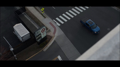 a blue truck driving down a street next to a tall building