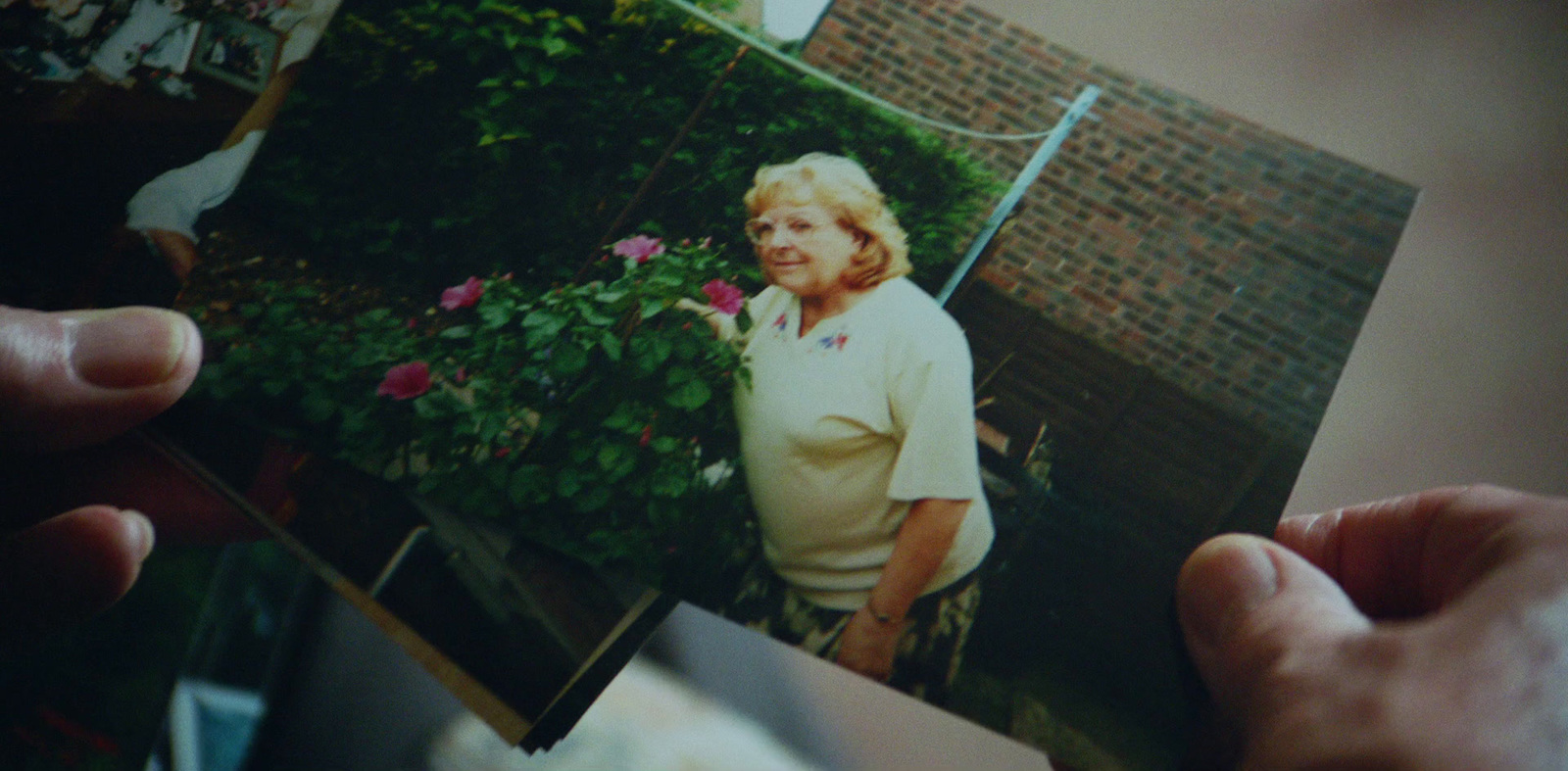 a person holding a picture of a woman in a garden