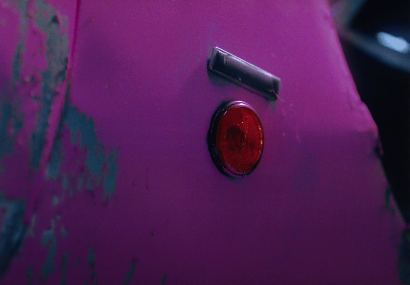 a close up of a pink car with a red light