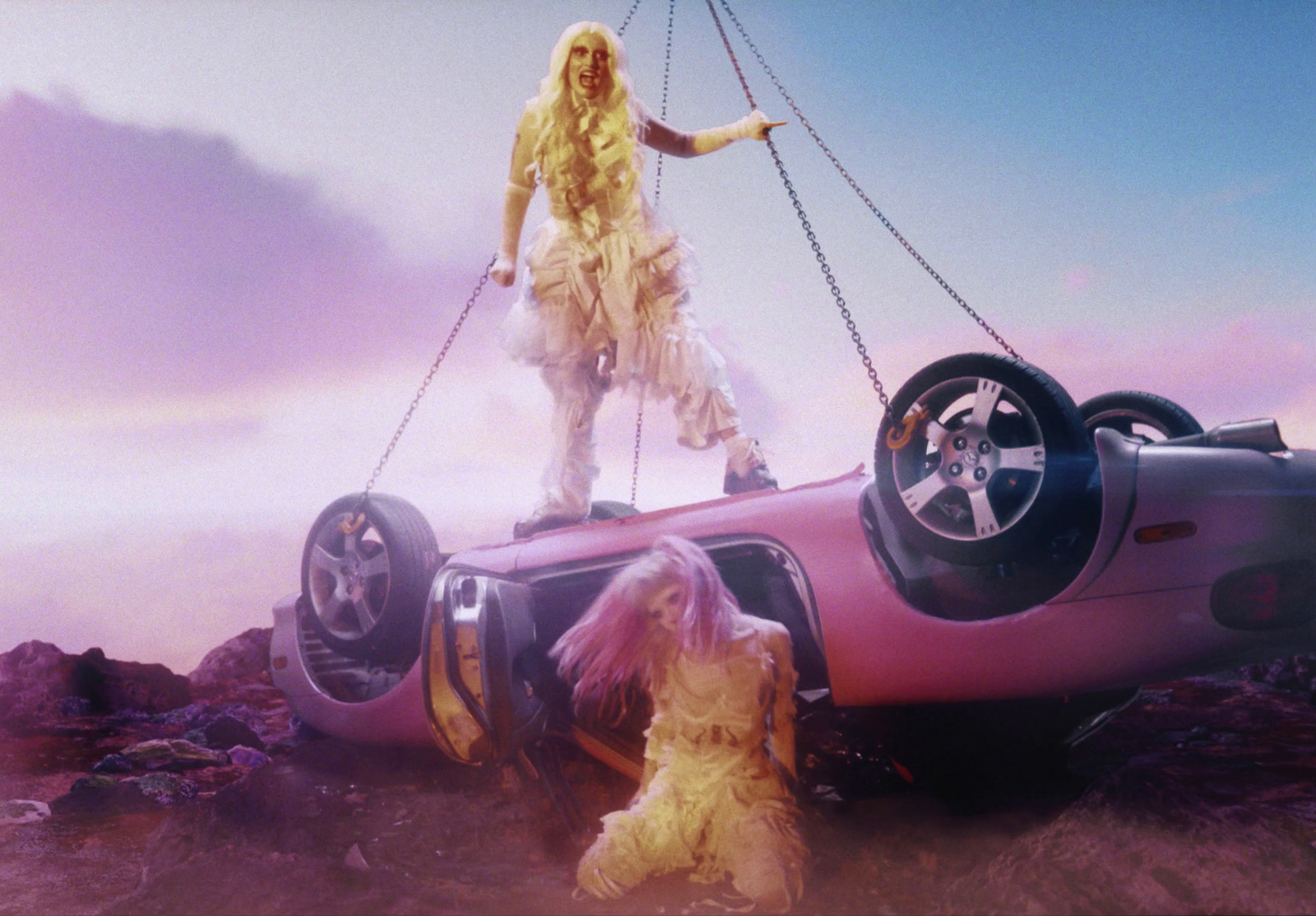 a woman standing on top of a car being lifted by a crane