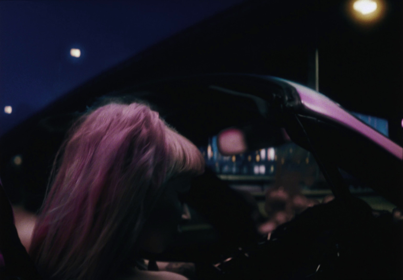 a woman with pink hair sitting in a car