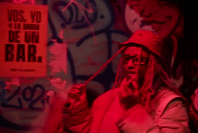 a man with dreadlocks standing in front of a graffiti covered wall