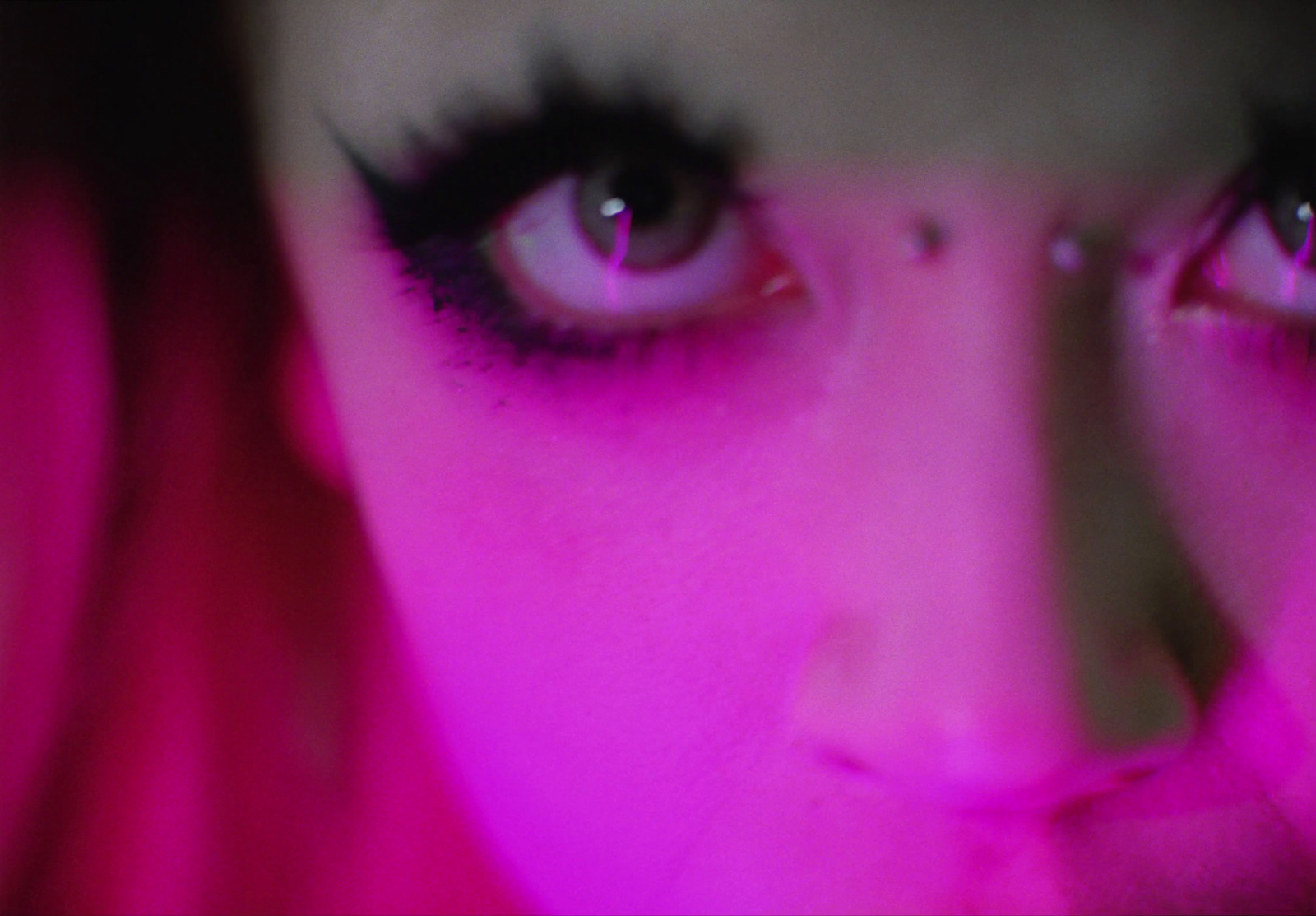 a close up of a woman's face with pink light