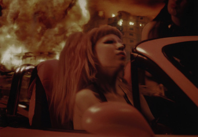 a woman leaning out the window of a car in front of a fire