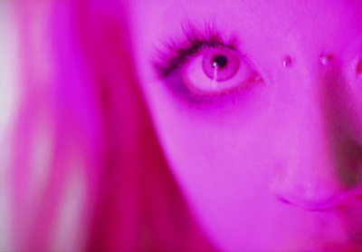 a close up of a woman's face with pink light