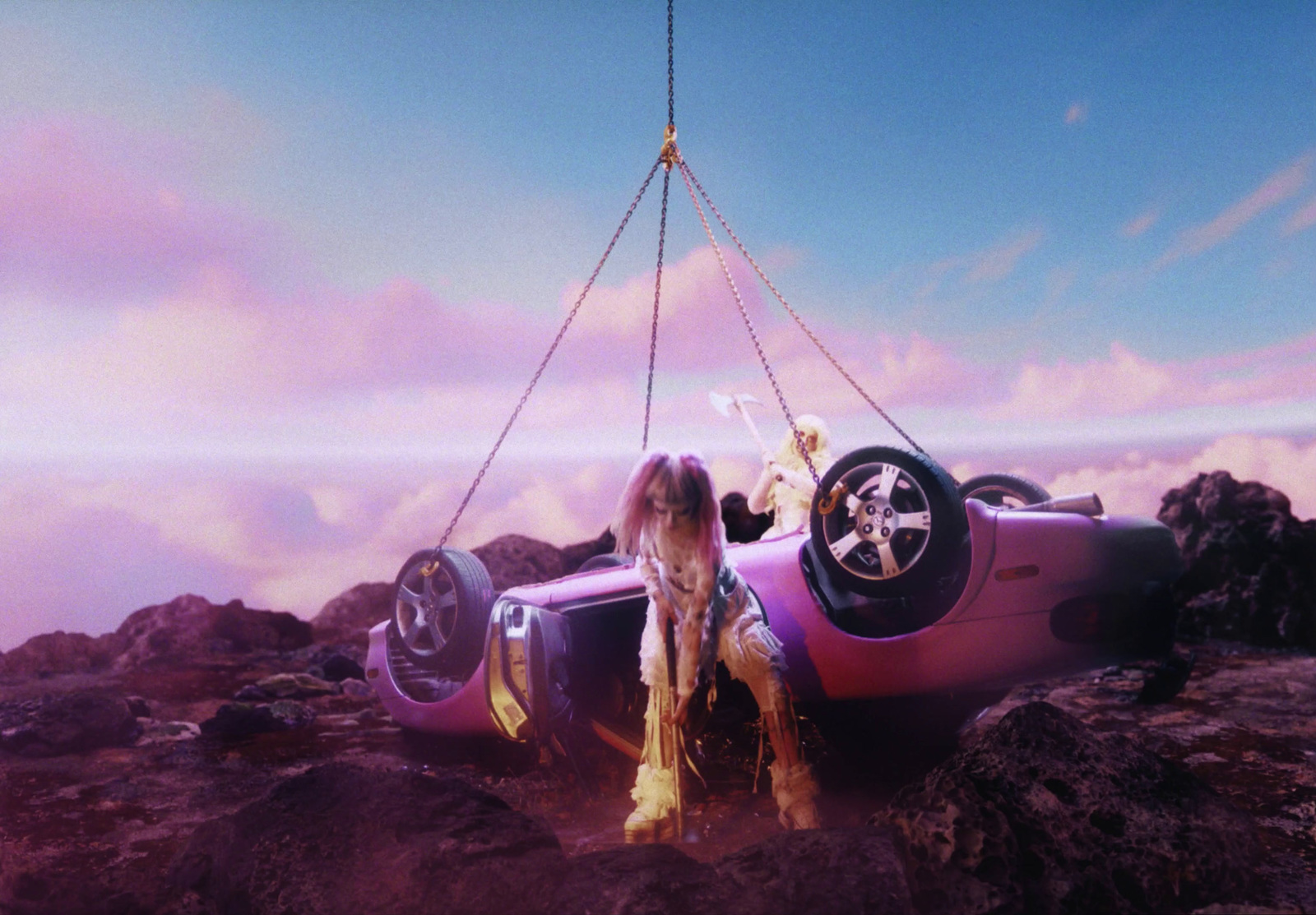 a dog sitting on top of a car being lifted by a crane