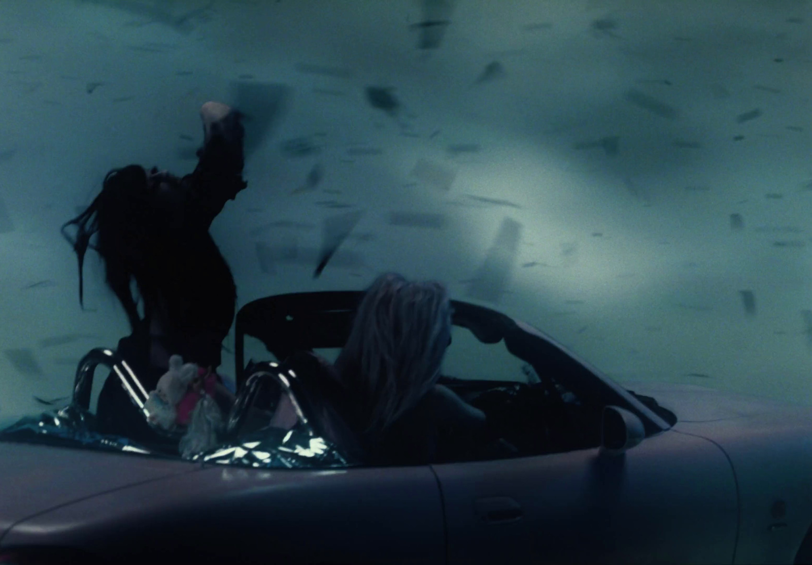 a woman sitting in a convertible car in a dark room