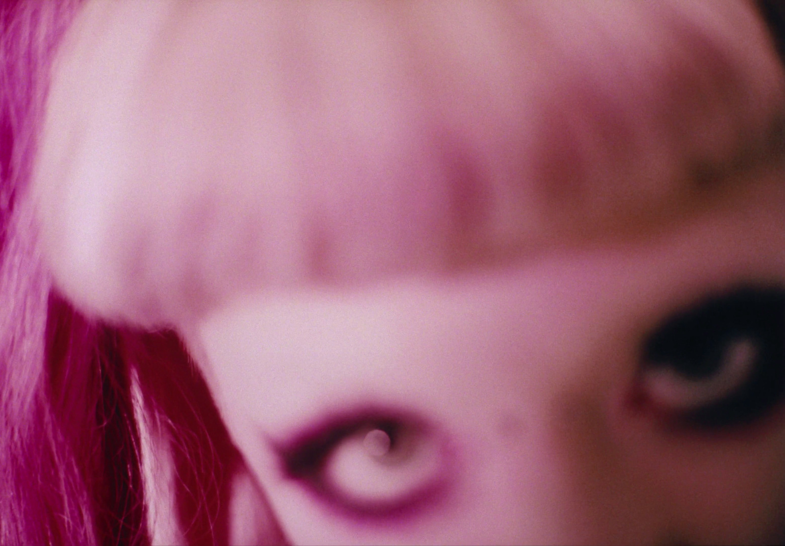 a close up of a woman's face with pink hair