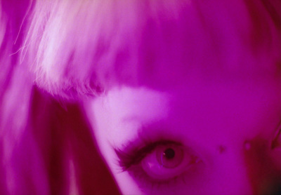 a close up of a woman's face with pink light